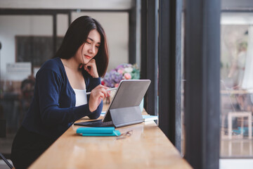Young asian woman thinking about new ideas during working on laptop computer at cafe.