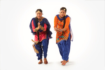 Two Giddha Dancers performing a dance step together.	