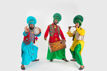 Three Bhangra Dancers playing Dafli,Dhol and Alghoza.	