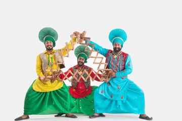 Three Bhangra Dancers depicting a dance step together with Saap.	