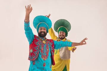 Two Bhangra Dancers performing a dance step with hand gestures.	