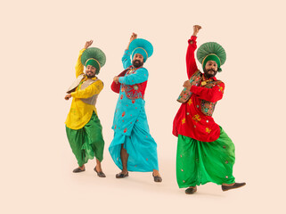 Three Bhangra dancers performing a dance step with hand gestures.	