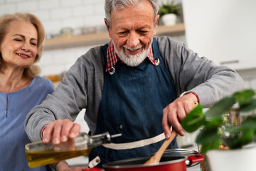 Senior woman and man cooking in the kitchen. Happy husband and wife preparing delicious food at home.