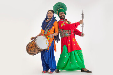 A Giddha dancer with a dhol and a Bhangra Dancer with Chimta representing folk dance.	