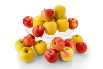 fuji apples and golden apples on clear glass raised plate, red and yellow fruits isolated on white background