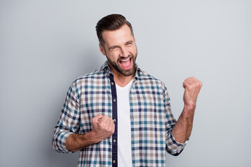 Photo of young attractive handsome crazy smiling positive excited man hold fists in victory isolated on grey color background