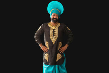 A man in Bhangra Costume standing with hands on his waist.	