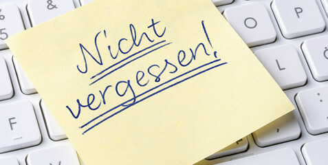 Sticky note on a keyboard - Do not forget in german - Nicht vergessen