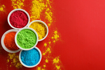 Colorful powders in bowls on red background, flat lay with space for text. Holi festival celebration