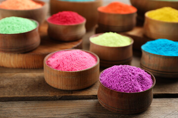 Obraz na płótnie Canvas Colorful powder dyes on wooden background, closeup. Holi festival