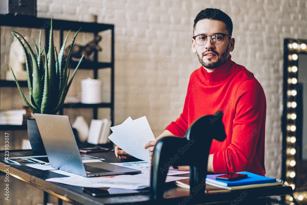 Poster portrait of young caucasian man in optical spectacles for provide eyes correction holding paperwork 
