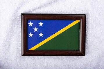 Solomon islands flag in a realistic frame on white cloth background flat lay photo.
