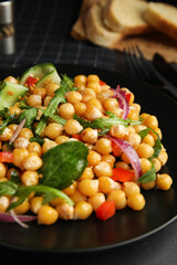 Delicious fresh chickpea salad on black table, closeup