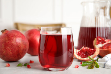 Glass of pomegranate juice and fresh fruits on light table