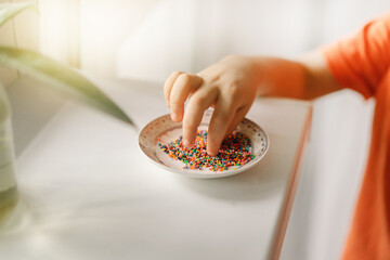 Cute boy eats and plays with Easter sprinkles.