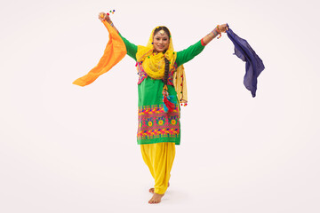 A Giddha dancer performing a dance step with colorful cloth.	