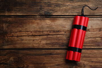 Red explosive dynamite bomb on wooden background, top view. Space for text