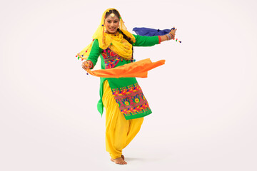 A Giddha dancer performing a dance step with colorful cloth.	