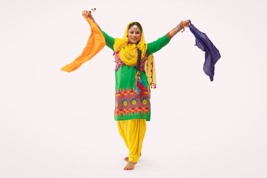 A Giddha dancer performing a dance step with colorful cloth.	