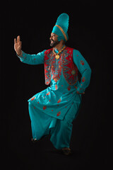 A Bhangra Dancer performing a dance step with hand gestures.	