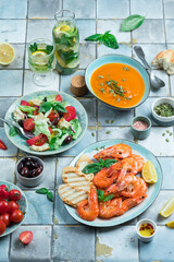 Mediterranean dishes at tiles table: seafood shrimps, vegetable salad, pumpkin soup, seeds and fruit lemonade