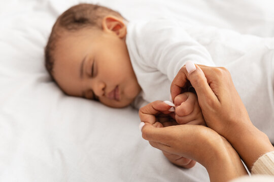 Loving Black Mom Holding Sleeping Baby's Hand Indoor, Selective Focus