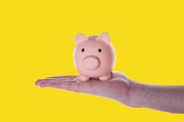 hand holding piggy bank on yellow background