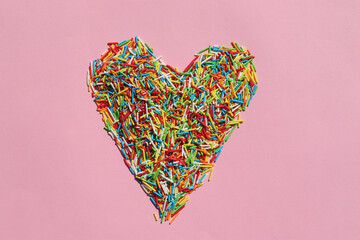 Heart shaped rainbow sugar sprinkle dots, decoration for cake and bakery on colored backdrop....
