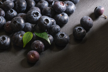 Fresh blueberries are scattered on a dark stone background. Products for a healthy diet. A source of vitamins. 