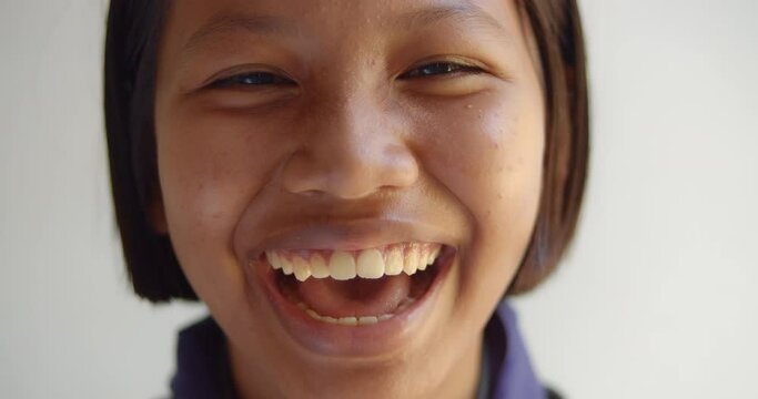 A native Asian black girl is beginning as a teenager with acne on her face and forehead is laughing happily.