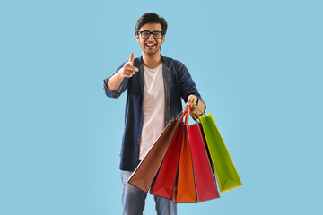 A young man standing with carry bags beckoning the onlooker.	