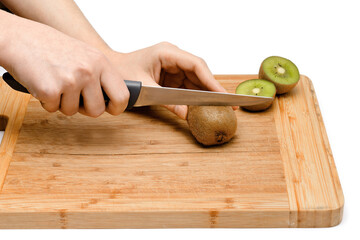 knife in hands kutting kiwi on a wooden board