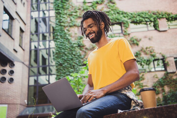 Photo portrait of young freelancer working on laptop outside home drinking coffee