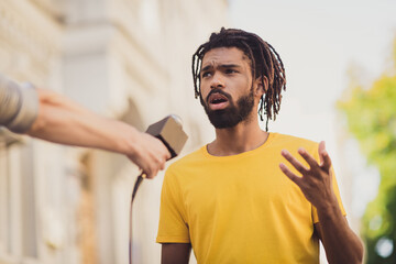 Photo portrait of young man giving interview on street speaking on camera for press television
