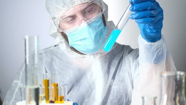 Scientific specialist in laboratory works chemical reagents. scientist wearing protective clothing gloves in lab conducts chemical experiments biological material. Holds test tube studies reaction