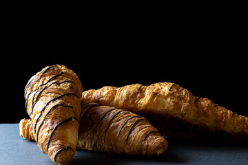 Croissant with chocolate. Freshly baked bread or french pastry croissants with jam on black bakery table. Tasty croissants with copy space.