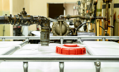 The large white tanks red lid of chemical open. Suction pipes for transferring to main storage tank inside of factory.