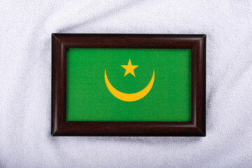 Mauritania flag in a realistic frame on white cloth background flat lay shot