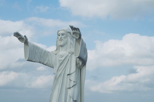Jesus statue standing and blessing with both the hands against blue sky background.