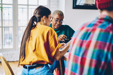Diverse female students analyzing information while preparing to exams together, multicultural group of people in casual clothes communicate during collaborative brainstorming in coworking space