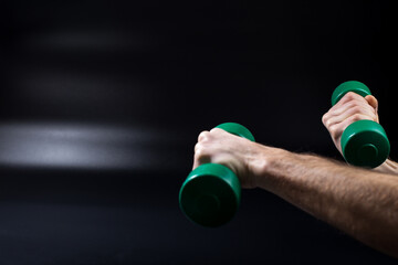 Exercises with dumbbells. Hands with dumbbells on black withcopy space.