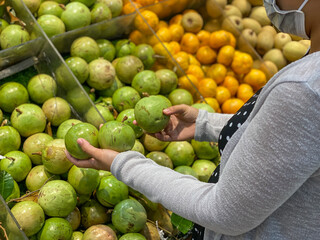 Woman wearing medical mask and buying caimito or star apple fruit 