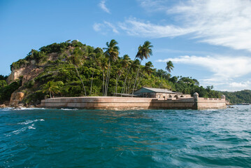 Morro de São Paulo Fortress on a sunny day. Blue sky, palm trees and forest.