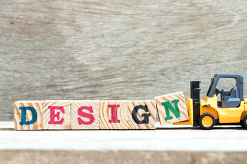 Fototapeta premium Toy forklift hold letter block n to complete word design on wood background