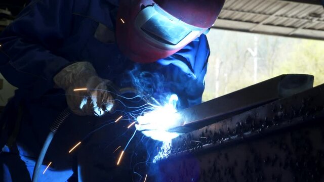 Anonymous workman welding metal construction in workshop