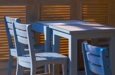 Sunlight and shadow on surface of dining table set with wooden wall on terrace of vintage restaurant