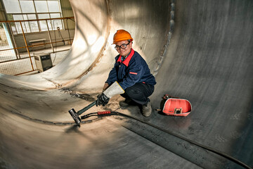 Asian workers use hammers to hit steel plates