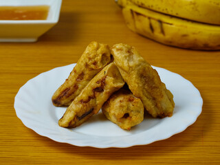 Delicious Fried slices of the ripe plantain on a white dish decorated with bananas and honey