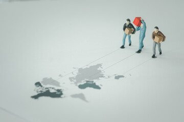 Miniature people of man carrying a parcel on a map to a recipient follow a way line. The concept of Worldwide courier service.