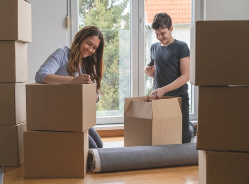 
Single mom with a teenage son controls a check list of things to move to new apartment.Brown cardboard boxes with copy space.Moving concept.